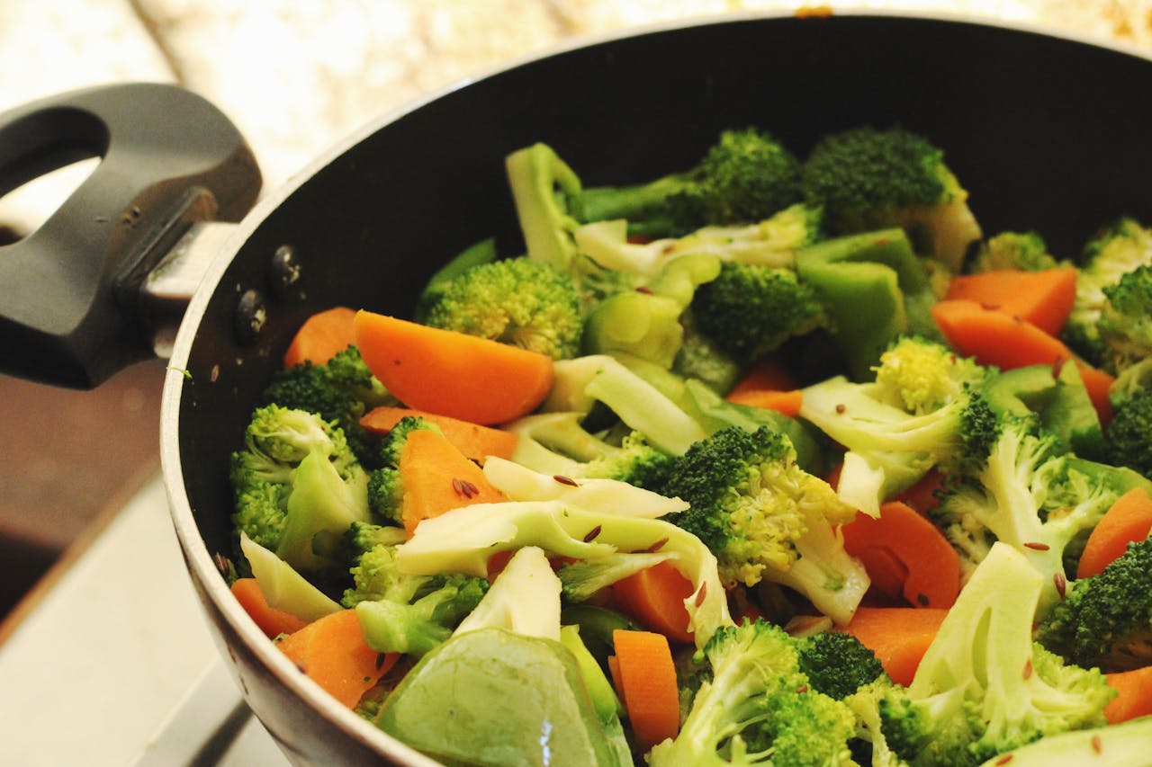 A vibrant mix of broccoli, carrots, and peppers cooking in a pan.